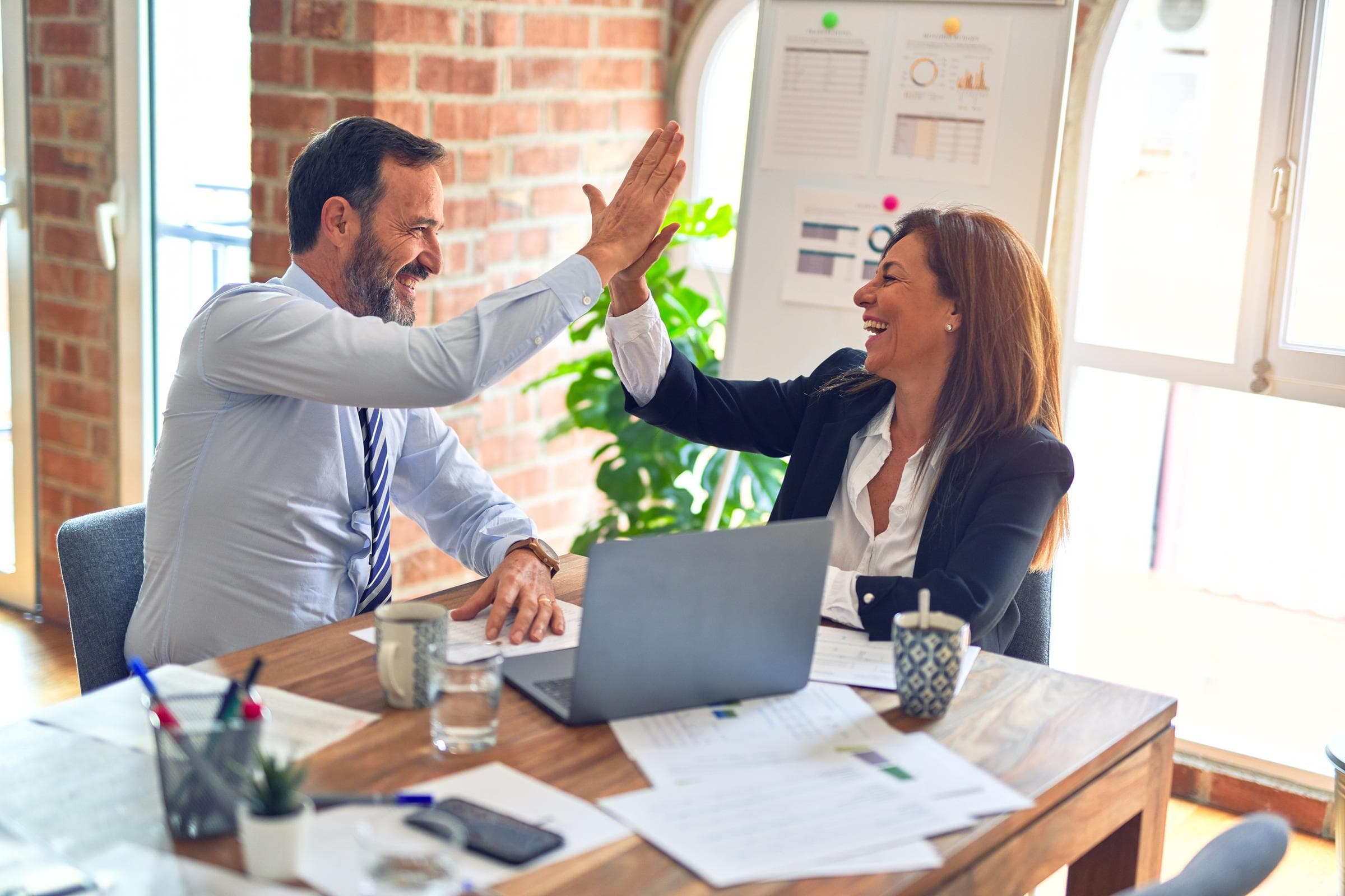 People in front of a laptop doing a high-five